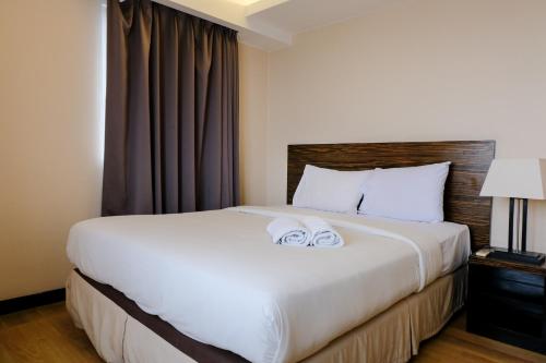 a bedroom with a large white bed with towels on it at Homey and Spacious 3BR Apartment at Braga City Walk By Travelio in Bandung