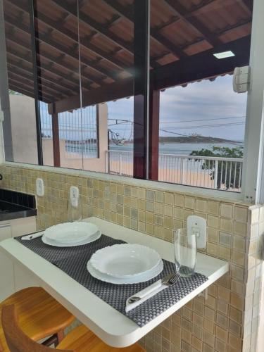 a kitchen counter with two white plates on it at Ipê Amarelo - Frente ao Mar na Praia de Meaípe, Guarapari in Guarapari