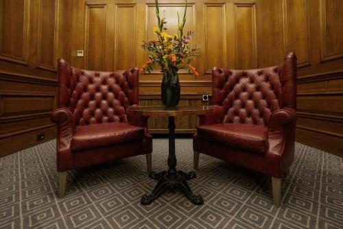 two chairs and a table with a vase of flowers at Kimpton Clocktower by IHG in Manchester