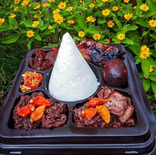 a tray of food with meat and a cone on top at Puri kahuripan in Kediri