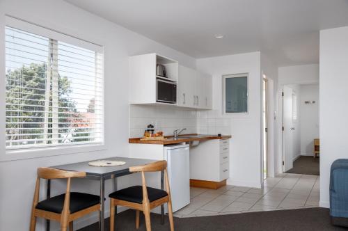 a kitchen with a small table and two chairs at Ocean Beach Wainui in Gisborne