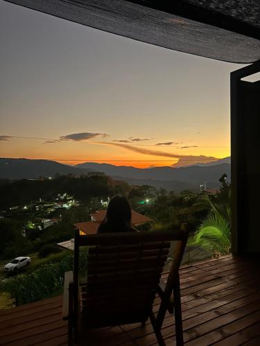 a person sitting in a chair on a deck watching the sunset at Cabaña Cedro Amarillo - moderna con jacuzzi en Sopetran, cerca de Medellín in Sopetran