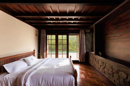 a bedroom with a bed and a large window at Marmaram Heritage in Vagamon
