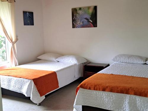 a bedroom with two beds and a picture on the wall at Iraka Campestre Quindio in El Edén