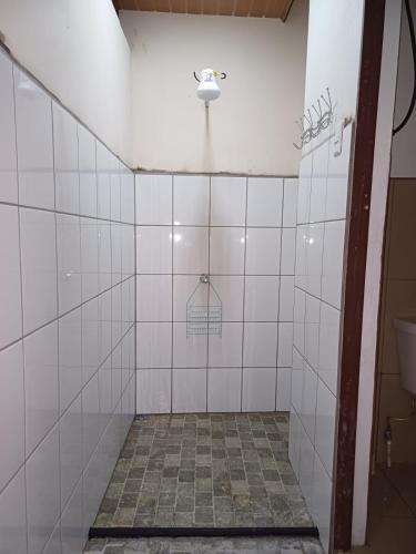 a bathroom with white tiled walls and a toilet at Sol De Fati in Quepos