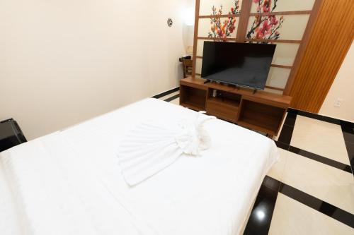 a bedroom with a white bed and a tv at ARA Gem Hotel in Ho Chi Minh City