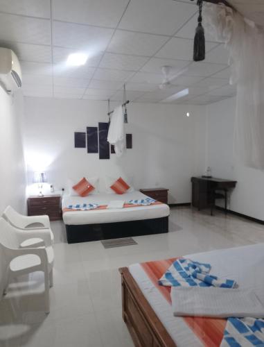 a bedroom with two beds and a desk in it at Sudunelum Holiday Resort in Anuradhapura