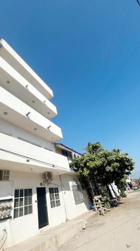 a white building with a tree in front of it at Apartment 4 Maleconcito del Sol Barra de Navidad in Barra de Navidad