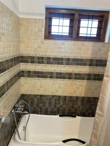 a bath tub in a bathroom with a window at Mountain Breeze Resort Vattavada in Munnar