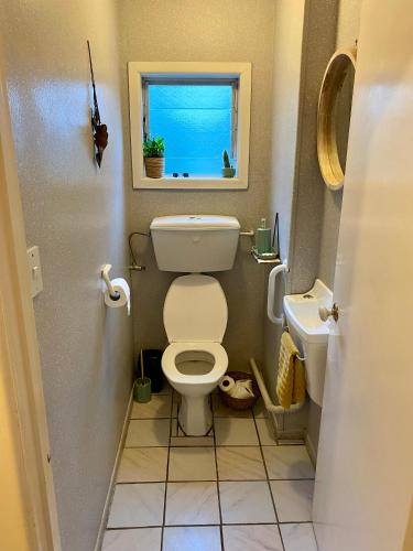 a small bathroom with a toilet and a window at Central Māngere Bridge Gem in Auckland