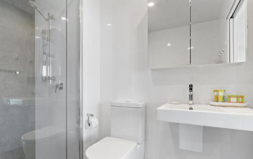 a bathroom with a toilet and a sink and a shower at Coastal Luxe - Beachfront - Reduced to end Mar 2026! in Newcastle