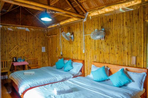 two beds in a bamboo room with blue pillows at SAKURA House - Vườn Đào in Mộc Châu