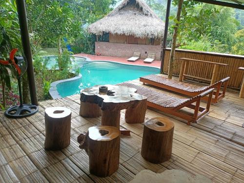 a patio with a table and logs in front of a pool at Puluong homestay1holiday in Pu Luong