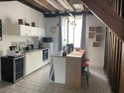 une cuisine avec des placards blancs et un îlot. dans l'établissement Orléans Le charme de l'ancien en hyper centre, à Orléans