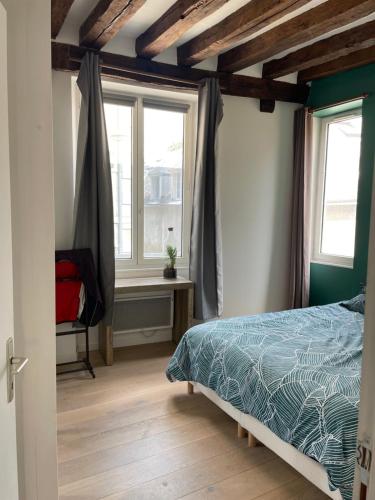 une chambre avec un lit et deux fenêtres dans l'établissement Orléans Le charme de l'ancien en hyper centre, à Orléans