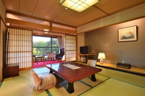 a living room with a wooden table and chairs at Yunogo Onsen HOTEL YUNOMORI BISYUNKAKU in Mimasaka
