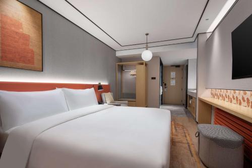 a bedroom with a white bed and a television at Hilton Garden Inn Chengde Mountain Resort in Chengde