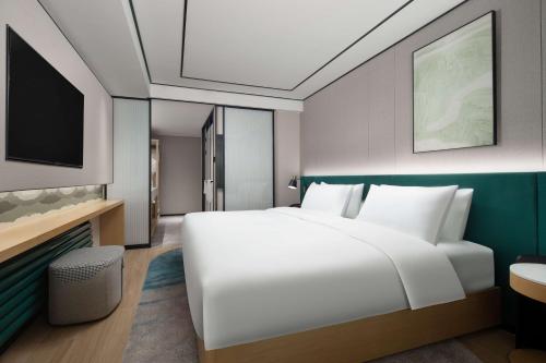a bedroom with a large white bed and a tv at Hilton Garden Inn Chengde Mountain Resort in Chengde