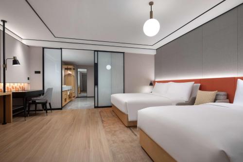 a hotel room with two beds and a desk at Hilton Garden Inn Chengde Mountain Resort in Chengde