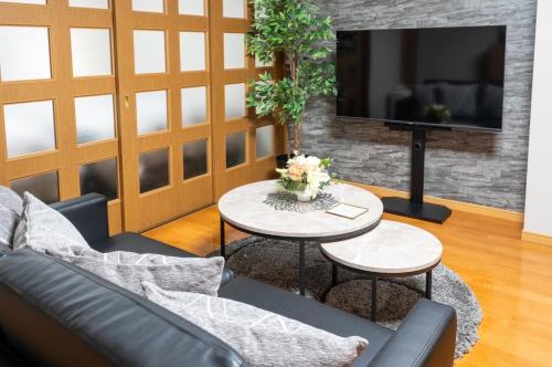 a living room with a couch and tables and a tv at Za086 柏原ビル101 in Tokyo