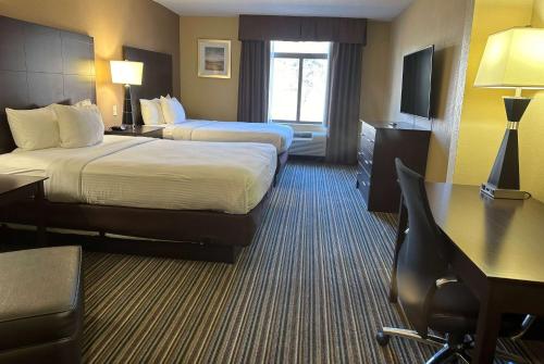 a hotel room with two beds and a desk at Wingate by Wyndham Harrisburg Near Hershey in Harrisburg