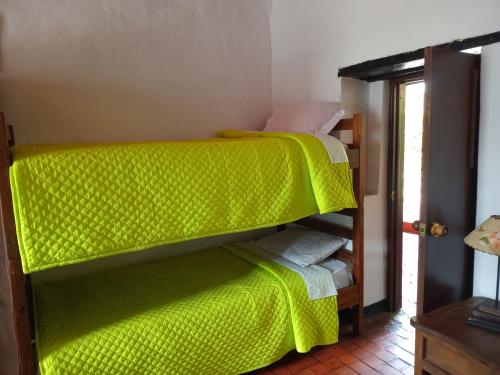 a bedroom with a bunk bed with a green blanket at Hostal Santa Isabel in Iza