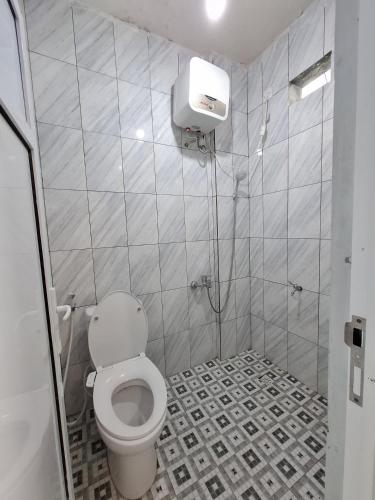 a bathroom with a toilet and a tiled floor at Hazuma Homestay in Tawangmangu