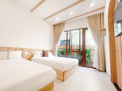two beds in a room with a window at BaPhu Apartment - 5BR - 5 mins walk to My Khe beach in Da Nang