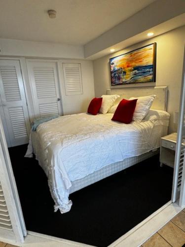 ein Schlafzimmer mit einem Bett mit zwei roten Kissen in der Unterkunft Five o clock somewhere in Golden Beach