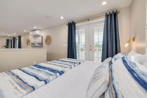 two beds in a bedroom with blue curtains at Downtown Dunedin Tiny Home w/ Pool in Dunedin