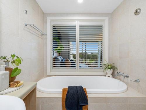 une baignoire blanche dans une salle de bains avec fenêtre dans l'établissement The Pool Resort Kingscliff - Studio with Garden View (5203) - Holiday Management Co., à Kingscliff