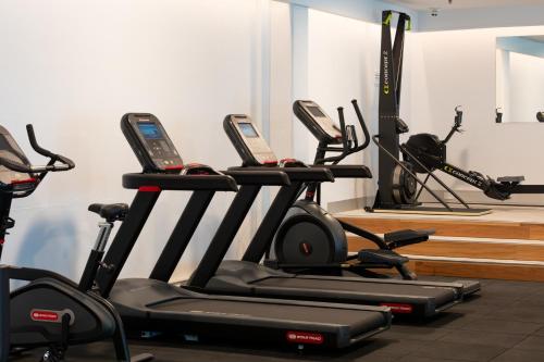 a gym with several treadmills and a row of exercise bikes at Rydges Canberra in Canberra