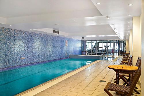 a swimming pool with a table and chairs in a building at Serain Chatswood Central in Sydney