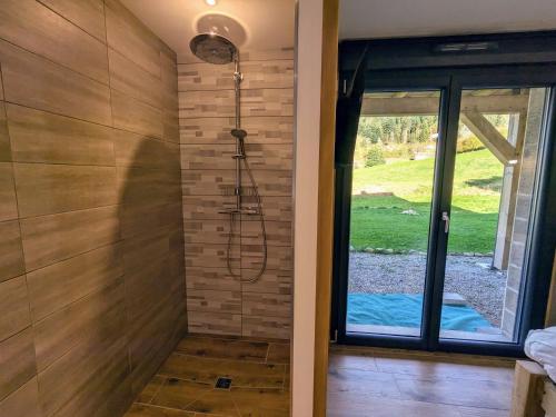 - une douche dans une chambre avec une porte en verre dans l'établissement Chalet grand confort avec sauna et balnéo - Proche stations de ski - FR-1-589-762, à Xonrupt-Longemer
