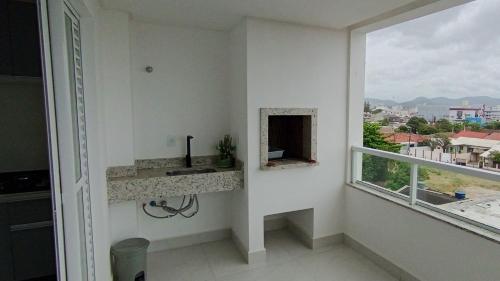 a bathroom with a sink and a window at Conforto perto do Mar, Aeroporto, Beto Carrero e Balneário in Navegantes
