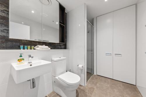 a white bathroom with a toilet and a sink at One Bedroom Private Apartment at 88 Archer St Chatswood in Sydney