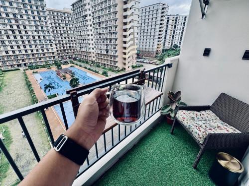 a person holding a glass of wine on a balcony at Hotel Rainy Smart Home Near Airport & Beach Luxury Comfort Bed in Lapu Lapu City