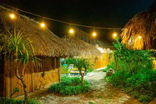 a resort with a straw hut with a table and palm trees at SAKURA House - Vườn Đào in Mộc Châu