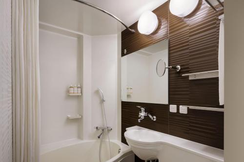 a bathroom with a tub and a toilet and a sink at Four Points Flex by Sheraton Kobe Sannomiya in Kobe