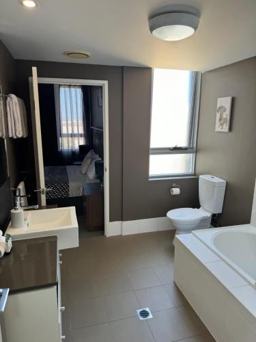 a bathroom with a toilet and a sink and a tub at Stunning Sub Penthouse in Gladstone