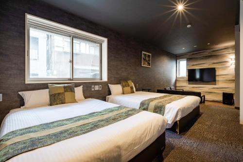 a hotel room with two beds and a flat screen tv at GRAND BASE Moji Nagomi in Kitakyushu