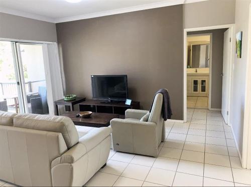 a living room with a couch and a tv at Modern Beach Apartment in Gladstone