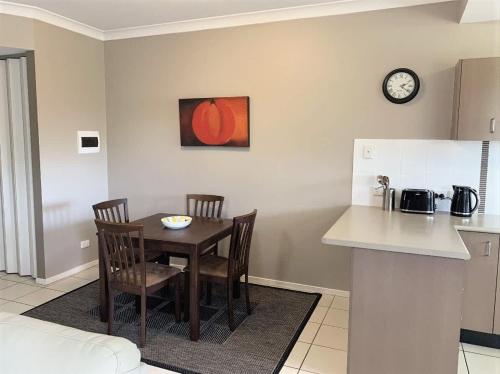a kitchen with a table and two chairs and a clock at Modern Beach Apartment in Gladstone
