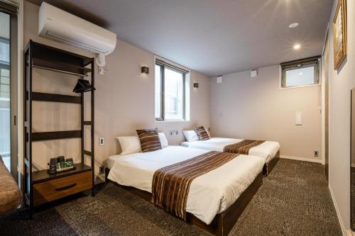 two beds in a room with two windows at GRAND BASE Moji Nagomi in Kitakyushu