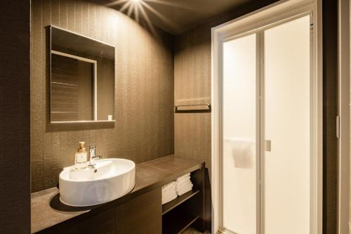 a bathroom with a sink and a mirror at GRAND BASE Moji Nagomi in Kitakyushu