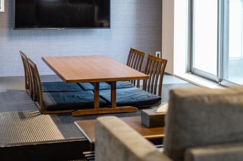 a wooden table with chairs and a couch in a room at GRAND BASE Moji Nagomi in Kitakyushu