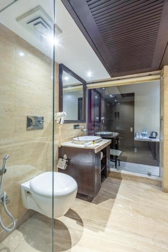 a bathroom with a toilet and a sink and a tub at Alaya Stays Hotel Emperor Palms in New Delhi