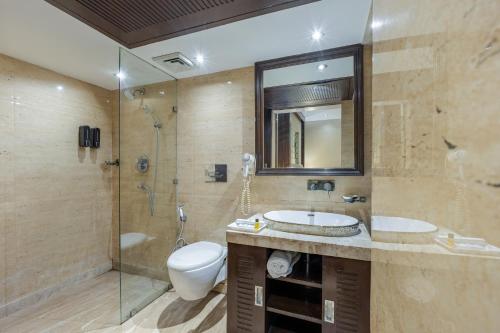 a bathroom with a toilet and a sink and a shower at Alaya Stays Hotel Emperor Palms in New Delhi