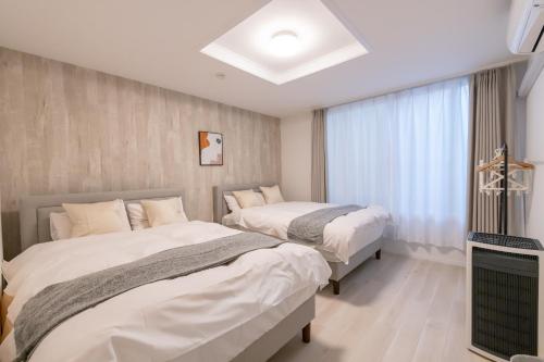 a bedroom with two beds and a window at 住舎桜ノ宮 in Osaka