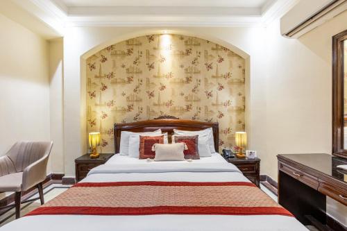 a bedroom with a large bed and a wall at Alaya Stays Hotel Emperor Palms in New Delhi